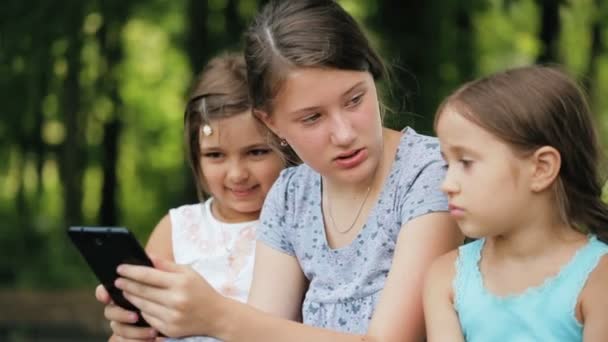 Drie meisjes zijn leuk om tijd doorbrengen met een digitaal tablet in een park. — Stockvideo