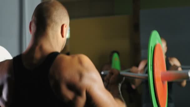 Un athlète fort lève la barre devant un miroir — Video