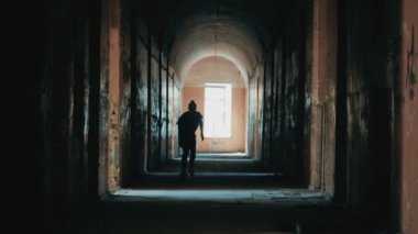 Terk edilmiş bir binada koridor boyunca bir kaykay üzerinde kaykaycı taşır.