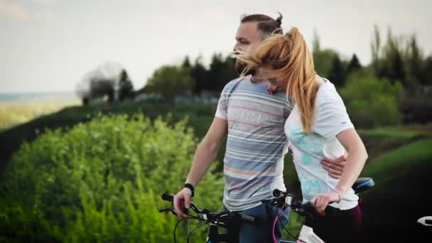 Um par de ciclistas na colina. O cara mostra a garota mais a rota . — Vídeo de Stock