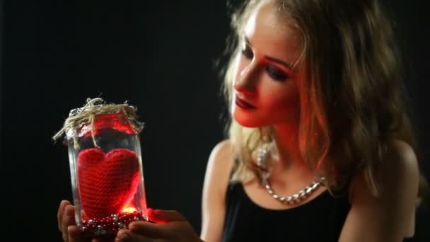 Симпатична дівчина оглядає сяюче серце в скляній банці . — стокове відео