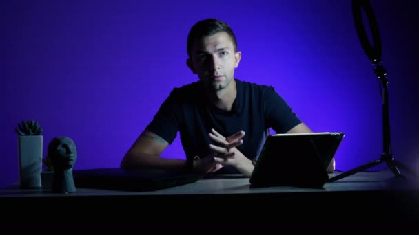 Blogger grabando opinión en video para redes sociales con luz led azul sobre fondo. — Vídeos de Stock