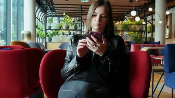 Nöjd flicka typer feedback på mobiltelefon i modern restaurang på hotellet — Stockvideo