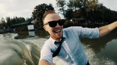 Aşırı iş adamının, takım elbiseli ve güneş gözlüklü halinin çekim kamerasındaki selfie 'si gölün sonundaki bir kayıtta suyun altına düşüyor.