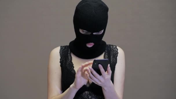 Femme ou petite amie en masque noir balaclava utiliser téléphone mobile de son mari, femme avec de gros seins habillés en sous-vêtements — Video