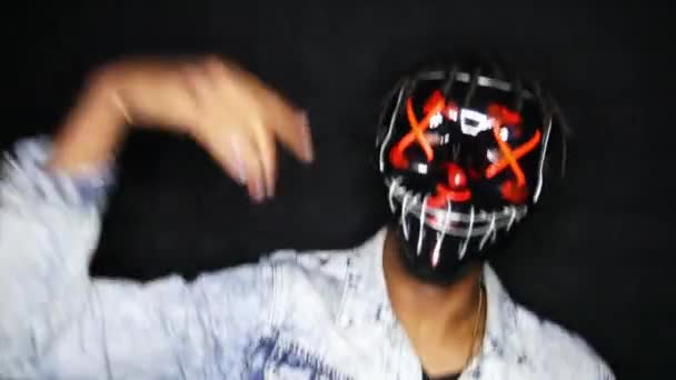Афроамериканець танцює під музику в масках у темній кімнаті. — стокове відео