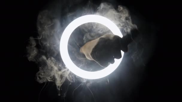 Mano con vapor y humo en cámara lenta pasa a través del círculo de luz sobre fondo negro. — Vídeo de stock