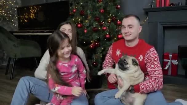 Щаслива сім'я з собакою телефонує родичам і друзям, бажає Веселого Різдва і Веселого Нового Року — стокове відео