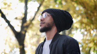 Gözlüklü ve şapkalı ciddi bir adamın portresi yavaş çekimde mesafeye bakıyor..