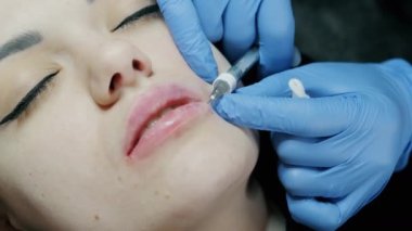 Güzel bir kadın kozmetoloji randevusunda dudak büyütme iğnesi yaptırıyor.