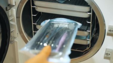 Laboratuvar çalışanı buharlı otoklav sterilizasyon makinesine tıbbi aletler yerleştiriyor.