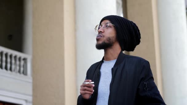 Elegante hombre pensativo toma una bocanada de un cigarrillo en cámara lenta, fuma en la calle — Vídeo de stock