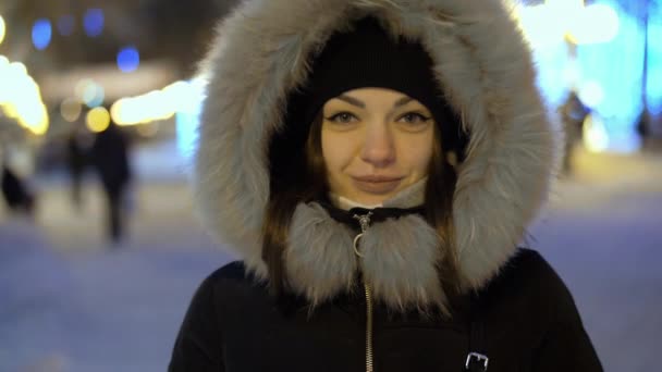Csinos fiatal nő áll a díszített utcán koszorúslámpával ünneplő karácsony és újév. — Stock videók