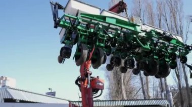 Manipülatör bir tarımsal ekiciyi yük arabasına yüklüyor.