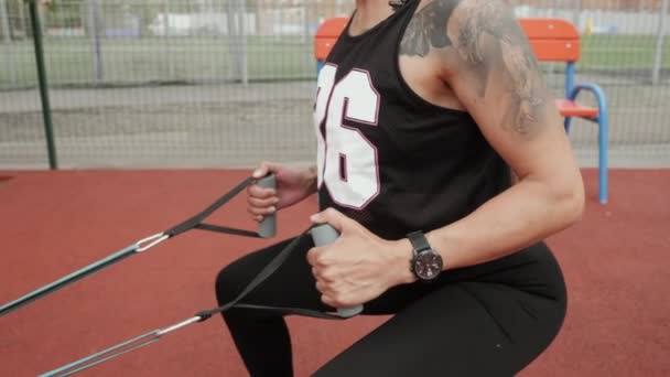 Atletik kadın spor sahasında spor yapmaya gider, göğsüne elastik bir bant takar. — Stok video