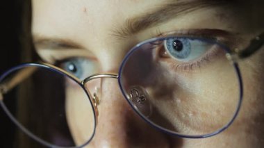 Gözlüklü genç bir kızın yakın çekimde gözleri monitöre bakar, oyun oynar, okur, ders çalışır.