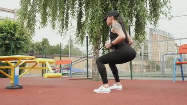 Atletik kadın spor sahasında spor yapmaya gider, göğsüne elastik bir bant takar. — Stok video