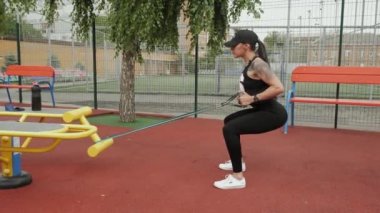 Atletik kadın spor sahasında spor yapmaya gider, göğsüne elastik bir bant takar.