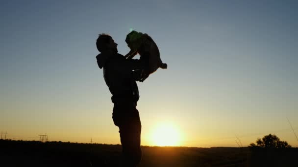 Man gooit een gelukkige pug hond in de lucht, knuffelt over zonsondergang hemel — Stockvideo