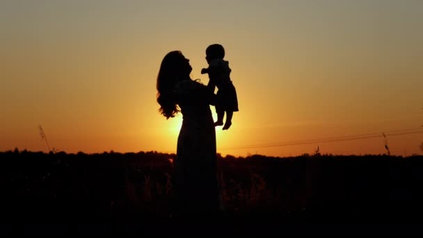 Silhueta irreconhecível ao pôr do sol, mãe feliz lança seu bebê — Vídeo de Stock