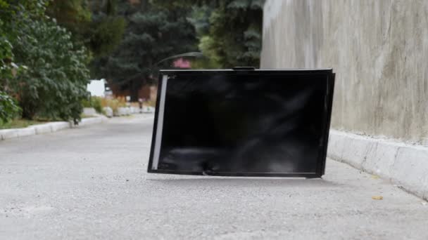 Moderní TV s plochou obrazovkou padá na asfalt z výšky a padá ve zpomaleném filmu — Stock video
