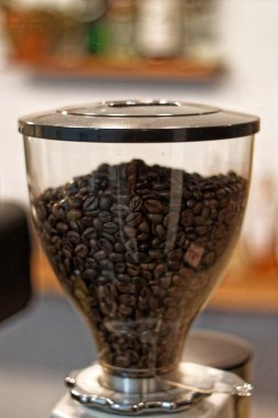 Kahve çekirdekleri taşıyan ve espresso malzemelerine dönüştürülmeye hazır öğütücü makinenin görüntüsü..