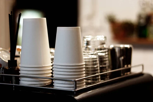 Kahve makinesinin üstüne, kahve dükkanının görünümünü güzelleştirirken alanı en aza indirmek için düzgünce yerleştirilmiş bardak ve bardak koleksiyonu..