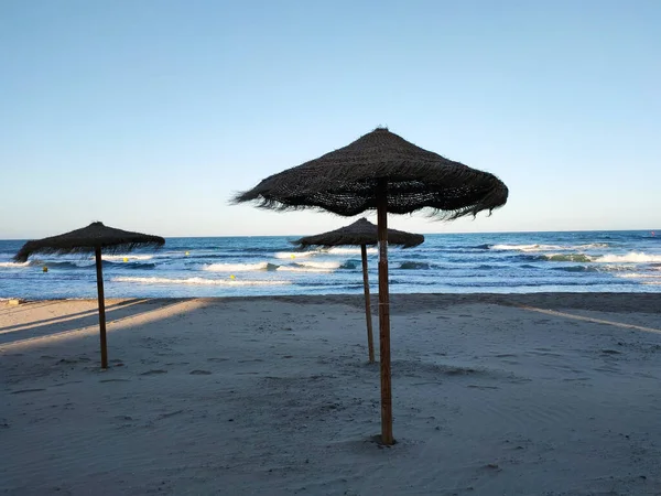 Opuštěná Pláž Slaměné Deštníky Kymácející Větru Pozadí Mořských Vln — Stock fotografie