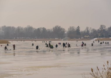 Donmuş nehir, bükük ve buzlu balıkçılar daha fazla balık yakalamak için donmuş bir nehir boyunca ilerliyorlar.