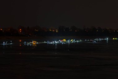 Donmuş nehir, gece ve buz balıkçıları karanlıkta yapay ışıklarla balık tutarlar ve herkes uykusunun ortasında bir şeritte birbiri ardına oturur.