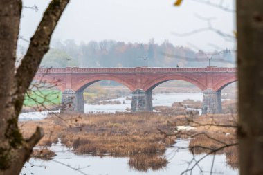 Sonbaharda eski bir tuğla köprü ve köprünün altından daha geniş sulara akan bir nehir.