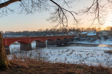 Nehrin üzerindeki eski bir taş ve kırmızı tuğladan köprü bazı yerlerde hala bir buz tabakası tarafından donduruluyor.