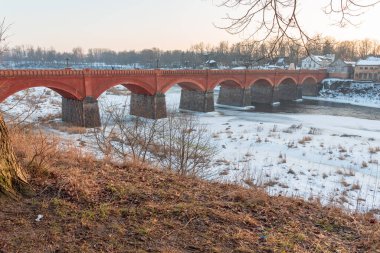 Nehrin üzerindeki eski bir taş ve kırmızı tuğladan köprü bazı yerlerde hala bir buz tabakası tarafından donduruluyor.