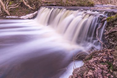 Birkaç aşamalı şelale ve düşen yapraklar kahverengidir ama kışın ardından bahar mevsiminde su akar.