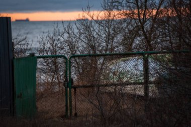 Denize giden yol kilitli antik metal bir kapıda bitiyor. Arkasında ufukta limana girmemizi bekleyen gemileri görebilirsiniz.