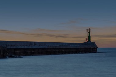 Baltık denizinde gün batımı nehrin denizle buluştuğu rıhtıma bakan ve sakin suların aktığı bir huzur hissi yaratıyor.