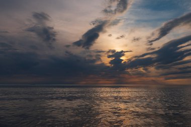sunset in the sea with clouds and calm water on the surface of which sunlight reflects by creating a light path