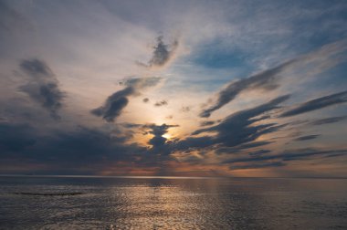sunset in the sea with clouds and calm water on the surface of which sunlight reflects by creating a light path