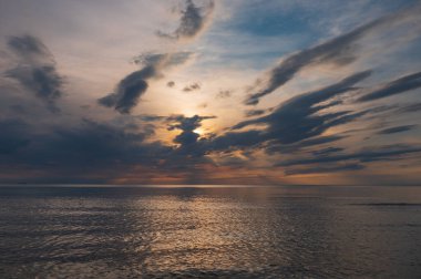 sunset in the sea with clouds and calm water on the surface of which sunlight reflects by creating a light path