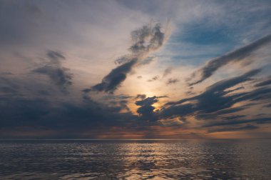 sunset in the sea with clouds and calm water on the surface of which sunlight reflects by creating a light path