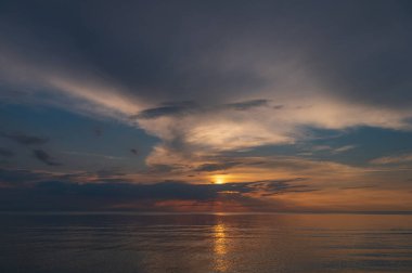sunset in the sea with clouds and calm water on the surface of which sunlight reflects by creating a light path