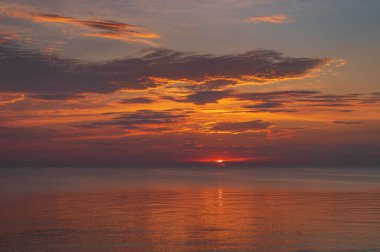 sunset in the sea with clouds and calm water on the surface of which sunlight reflects by creating a light path