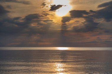 sunset in the sea with clouds and calm water on the surface of which sunlight reflects by creating a light path