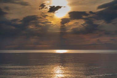 sunset in the sea with clouds and calm water on the surface of which sunlight reflects by creating a light path