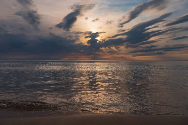 sunset in the sea with clouds and calm water on the surface of which sunlight reflects by creating a light path