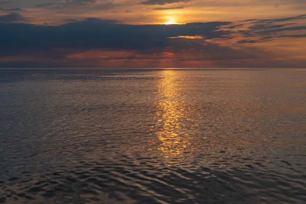 sunset in the sea with clouds and calm water on the surface of which sunlight reflects by creating a light path