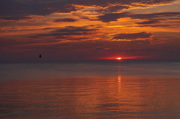 sunset in the sea with clouds and calm water on the surface of which sunlight reflects by creating a light path
