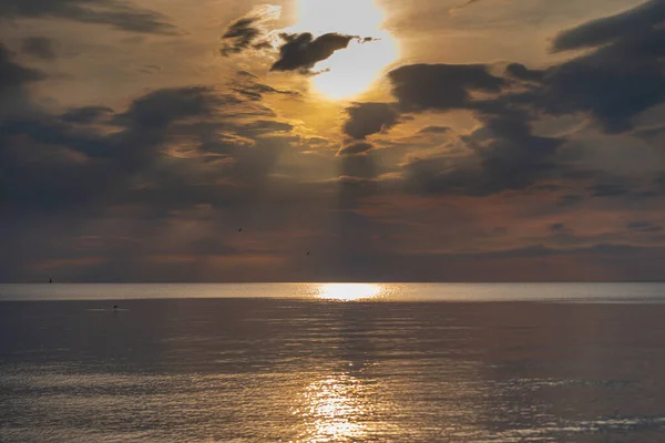 sunset in the sea with clouds and calm water on the surface of which sunlight reflects by creating a light path