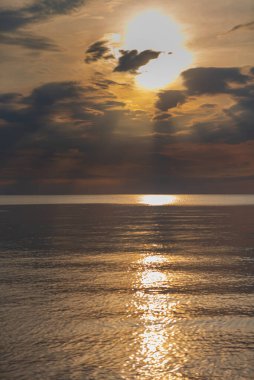 sunset in the sea with clouds and calm water on the surface of which sunlight reflects by creating a light path