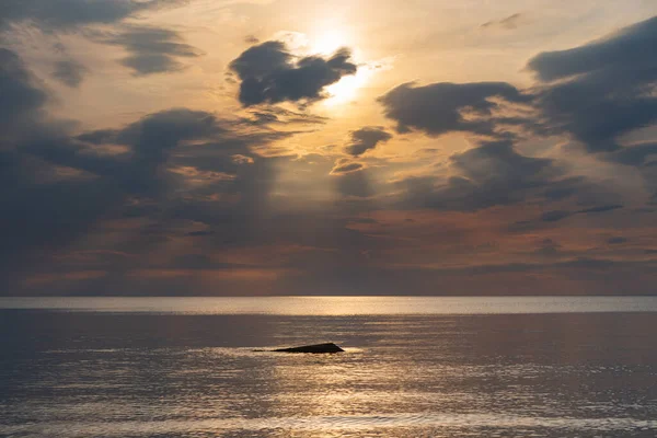 sunset in the sea with clouds and calm water on the surface of which sunlight reflects by creating a light path